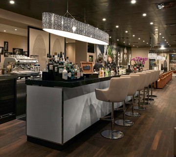 Moderne Bar mit vielen Drinks, Siebträger-Kaffeemaschine und Drehhocker