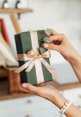 Wrapped gift with green paper, bow and eucalyptus branch